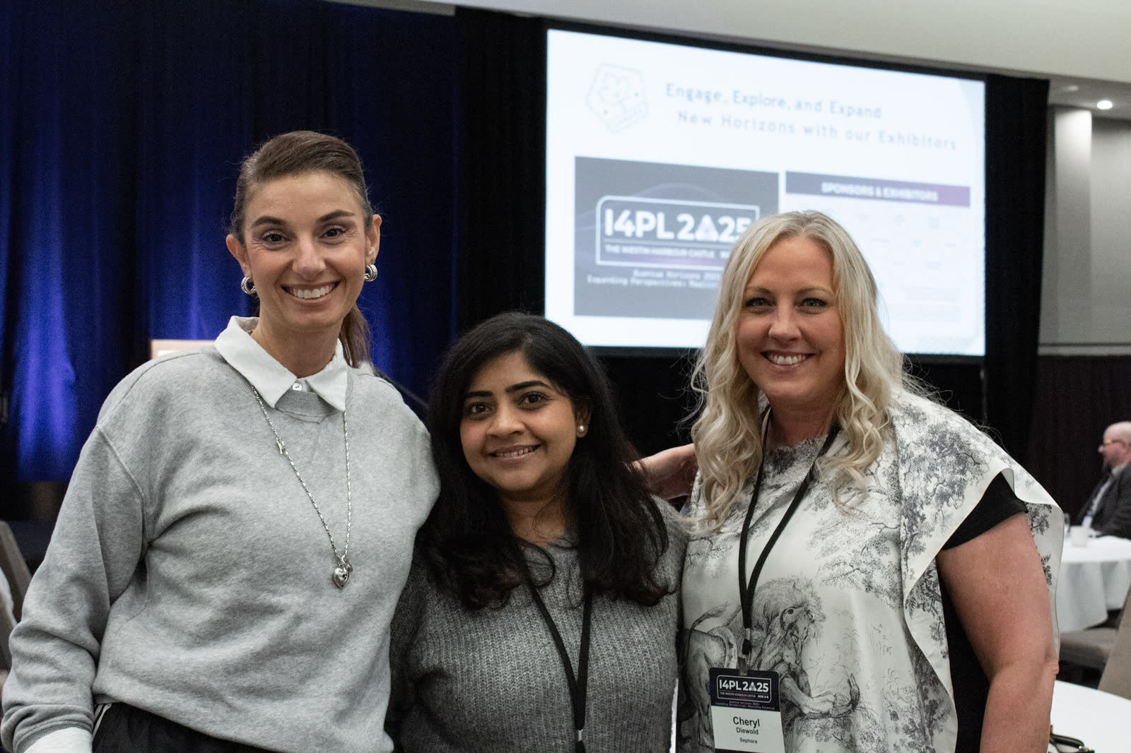 Three I4PL delegates together in front of the main stage screen